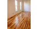 Bright empty room featuring hardwood floors and two windows, creating a warm and inviting space at 6967 Bluffridge Way, Indianapolis, IN 46278