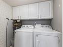 Convenient laundry room equipped with white cabinetry, modern appliances, and stylish wallpaper at 1014 Sugar Maple Dr, Greenwood, IN 46143