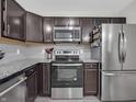 Modern kitchen with stainless steel appliances, granite countertops, dark cabinetry and a tile backsplash at 10844 Tedder Lake Dr, Indianapolis, IN 46239