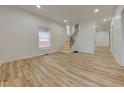 Bright living room with light hardwood floors, staircase, and ample natural light from the large windows at 1360 N Dearborn St, Indianapolis, IN 46201