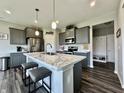 Modern kitchen featuring sleek gray cabinets, marble countertops, pendant lighting, stainless steel appliances, and dark hardwood floors at 1380 Delacorte Cir, Shelbyville, IN 46176
