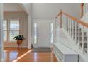 Bright foyer with gleaming hardwood floors, staircase, and a bench with storage at 1950 Midnight Pass, Brownsburg, IN 46112