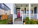Inviting front porch with a red door, white railings, and lush greenery at 2023 Alvord St, Indianapolis, IN 46202