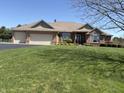 Brick house with a three-car garage surrounded by green grass and a mature tree providing shade at 415 N Westview Dr, Columbus, IN 47201