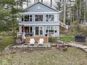 Beautifully landscaped backyard featuring a patio, fire pit, and a charming light blue two story lake house at 6599 Meadowlark Dr, Nineveh, IN 46164
