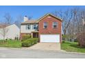 Classic two-story home featuring a brick facade, attached garage, and green lawn at 7418 Bluebird Ct, Indianapolis, IN 46254
