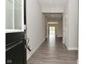 Long hallway with hardwood floors, neutral walls, and natural light streaming in from the open doorway at 10319 Pronghorn Ln, Indianapolis, IN 46239