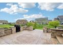 Spacious backyard patio with stone seating area, landscaping, and black grill at 13494 Moorcroft Dr, Fishers, IN 46037