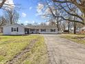 Charming single-story home featuring light blue siding, dark shutters, a fountain, and a paved driveway at 1707 W 76Th Pl, Indianapolis, IN 46260