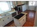 Bright kitchen featuring granite countertops, a central island with cooktop, stainless steel appliances, and wood flooring at 3790 E Pleasant Run Parkway North Dr, Indianapolis, IN 46201