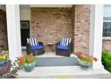 Cozy front porch with striped cushioned chairs, potted flowers, and a welcoming ambiance at 4415 Voyageur Way, Carmel, IN 46074