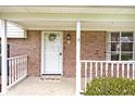 Inviting front porch with brickwork, white railing, 'welcome' mat, and a decorative wreath on the door at 6436 Lakeland Blvd, Indianapolis, IN 46234