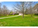 A serene shot of a brick home with a long driveway, nestled amongst mature trees and a lush green lawn at 6761 E Woodland Ct, Mooresville, IN 46158