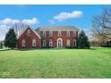 Attractive two-story brick home with mature trees and a well-maintained lawn on a sunny day at 7265 Derbyshire Dr, Cumberland, IN 46229
