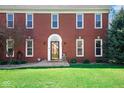 Elegant red brick home featuring a classic arched doorway and manicured front lawn at 7265 Derbyshire Dr, Cumberland, IN 46229