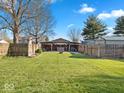 Large grassy backyard featuring a wooden fence, fire pit and cabana at 919 Oak Park Dr, Shelbyville, IN 46176