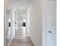 Hallway featuring light wood floors, white trim, and a large mirror at 15702 Cobbs Crk Ln, Noblesville, IN 46060