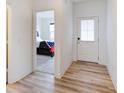 Hallway featuring light wood floors, a white door, and a view of a bedroom at 15702 Cobbs Crk Ln, Noblesville, IN 46060