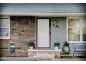 Inviting front door with brick accents, potted flowers, a small bench, and visible house number at 2126 Dawnshire Dr, Columbus, IN 47203