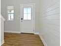 Bright entryway featuring a decorative front door, shiplap accent wall, and wood-look flooring at 321 Bluestem Ln, Whiteland, IN 46184