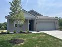 Lovely single-story home featuring a grey brick facade, a well-manicured lawn, and a young tree at 3949 Donaldson Creek Ct, Clayton, IN 46118