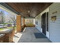 Spacious covered front porch featuring brick pillars, dark wood ceiling, and a charming porch swing at 3970 Broadway St, Indianapolis, IN 46205
