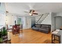 Bright living room featuring hardwood floors, a ceiling fan, and easy access to the staircase at 5945 Mcfarland Rd, Indianapolis, IN 46227