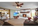 Cozy living room featuring a brick fireplace, neutral carpet, and ceiling fan with views into the kitchen at 7608 Andrew Turn, Plainfield, IN 46168