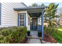 Inviting front porch with a decorative welcome sign, a blue mat and potted plants at 8506 Friendship Ln, Indianapolis, IN 46217