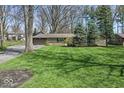 Beautifully landscaped front yard with lush green grass and mature trees at 10129 Guilford Ave, Carmel, IN 46280