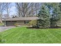 Well-maintained front yard with green grass, mature trees, and shrubbery at 10129 Guilford Ave, Carmel, IN 46280