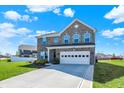 Inviting two-story brick home featuring a pristine lawn, garden bed, and two-car garage at 10465 Long Branch Dr, Brownsburg, IN 46112