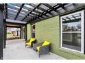 View of a covered patio with black pergola and chairs with bright yellow cushions, adjacent to the brick home at 2103 Postmaster Ln, Greenfield, IN 46140