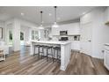 Open concept kitchen with white cabinets, a center island, modern pendant lighting, and wood-look vinyl plank flooring at 2741 Penn Ave, Plainfield, IN 46168