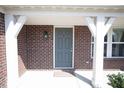 Welcoming front entry featuring a covered porch with brick columns and a gray front door at 5051 Arling Ct, Indianapolis, IN 46237