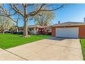 Brick home featuring a spacious driveway leading to an attached garage and a well-manicured lawn at 5124 Mccray St, Indianapolis, IN 46224