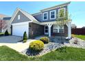 Well-maintained front yard with beautiful rock beds and healthy green grass leading up to a brick-accented facade at 5493 W Woodhaven Dr, McCordsville, IN 46055