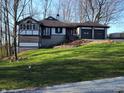 Charming home with a two-car garage, stone accents, and lush green lawn at 5739 E 62Nd Pl, Indianapolis, IN 46220