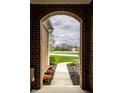 View from brick arch looking out onto a green lawn, walkway, and pond at 6049 Royal Gate Pl, Indianapolis, IN 46237