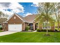 Beautiful brick home featuring a lush green lawn, attached garage, and meticulously landscaped front yard at 6049 Royal Gate Pl, Indianapolis, IN 46237