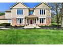 Lovely home entrance with lush green lawn, complemented by a red door and classic brick and siding at 611 Mill Farm Rd, Noblesville, IN 46062
