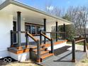 Inviting covered porch with stained wood trim, gray decking, and a modern cable railing system at 7440 S 250 W, Pendleton, IN 46064