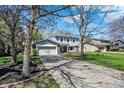 View of home showcasing the driveway, lawn and tree lined front yard at 7728 Mallard Way, Indianapolis, IN 46256