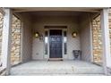 Welcoming covered front porch with double doors, sconces, and stone accents at 11203 Westminster Way, Carmel, IN 46033