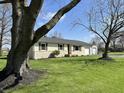 Inviting single-story home with a brick facade, complemented by a lush green lawn and mature shade trees at 1210 W Grant St, Thorntown, IN 46071
