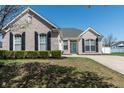 Charming brick home with a manicured lawn, dark shutters, and a pop of color on the front door at 122 Stamford Dr, Pittsboro, IN 46167