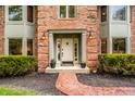 Inviting entryway with a brick path leading to a classic front door and manicured bushes at 12613 Carrington Pl, Carmel, IN 46033