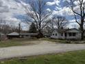 A wide view of the white home from the street, surrounded by lawns and mature trees at 130 Hiawatha Dr, Noblesville, IN 46062