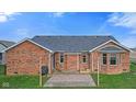 A backyard showcasing a red brick house with a stone patio, and a green lawn at 2511 Countryside Westview Dr, Shelbyville, IN 46176
