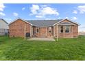 Exterior of a red brick house with a well-maintained backyard featuring a stone patio and green lawn at 2511 Countryside Westview Dr, Shelbyville, IN 46176